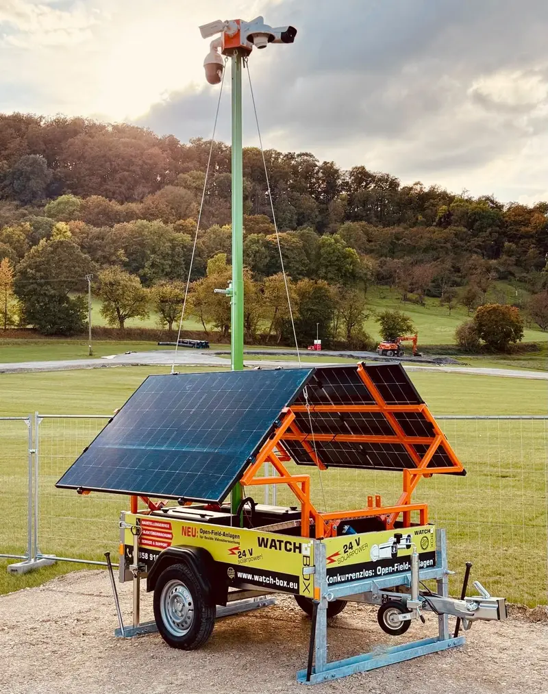 Mobile Ueberwachungsanlage mit Solarpanels und Kamera auf gruenem Mast